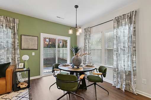 A dining room with a table set for four and a view of a backyard.