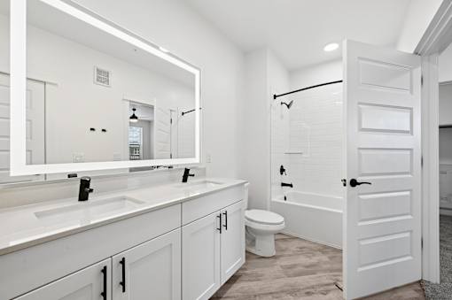A white bathroom with a toilet, sink, and mirror.