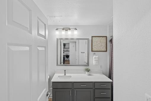 A bathroom with a sink, mirror, and cabinets.