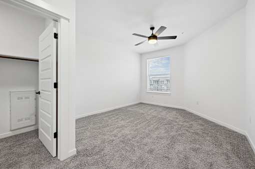 A room with a ceiling fan and a window with blinds.