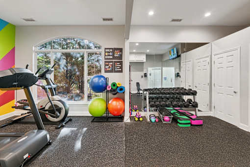 A gym room with a treadmill, exercise balls, and weights.