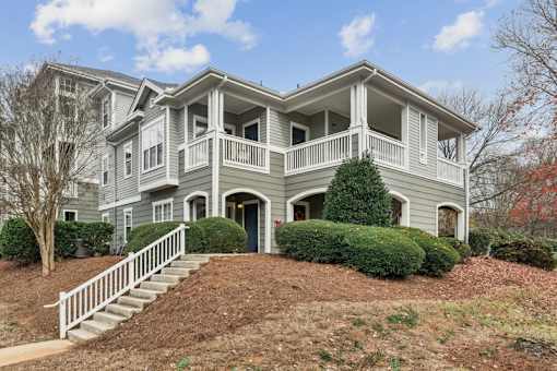 A grey two-story house with a white staircase leading to the entrance.