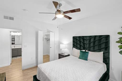 A bedroom with a bed, a ceiling fan, and a lamp.