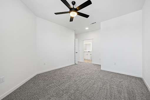 A room with a ceiling fan and carpeted floor.