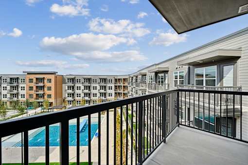 A balcony with a pool and apartment buildings in the background.