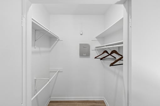 A white closet with two shelves and a coat hanger.