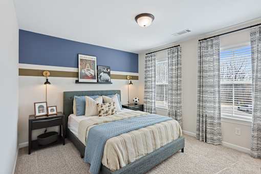 A bedroom with a bed, nightstand, and framed pictures on the wall.
