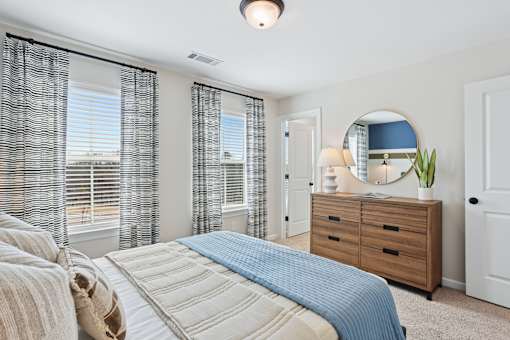 A bedroom with a large bed, a dresser, and a mirror.
