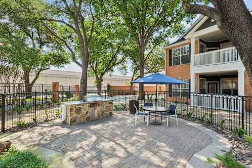 A patio with a table and chairs is surrounded by a black fence.
