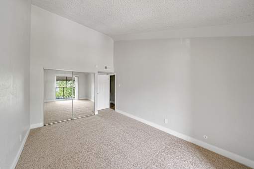 A large empty room with a carpeted floor and a sliding glass door.