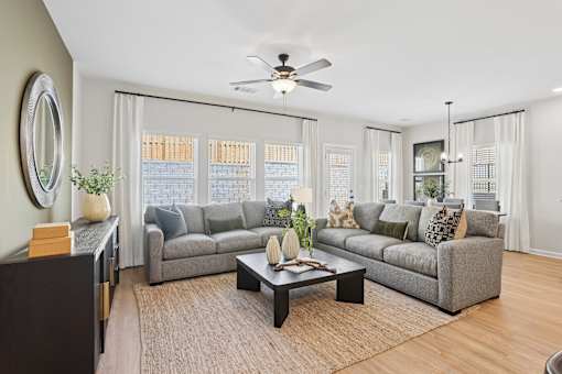 A living room with a grey couch, a coffee table, and a ceiling fan.