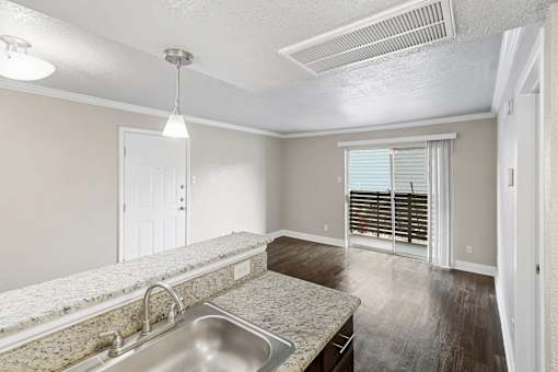 A kitchen with a granite countertop and a stainless steel sink.