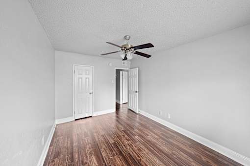 A room with a ceiling fan and wooden floors.