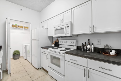 a kitchen with white cabinets and appliances and a white refrigerator