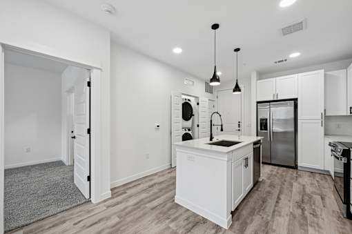 A modern kitchen with white cabinets and a wooden floor.