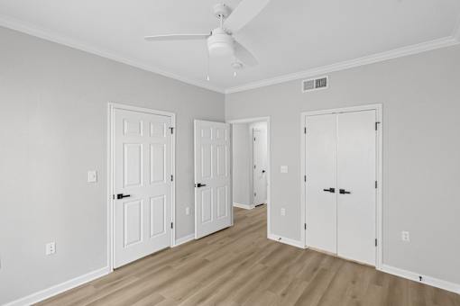 A room with a ceiling fan and three doors.