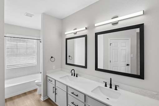 A white bathroom with a sink, mirror, and bathtub.