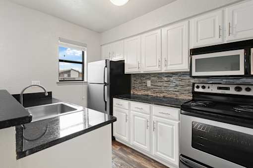 A kitchen with black countertops and white cabinets.