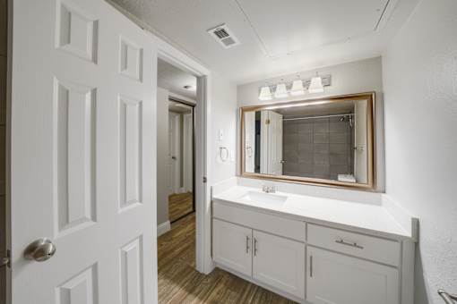 A white bathroom with a mirror and a sink.