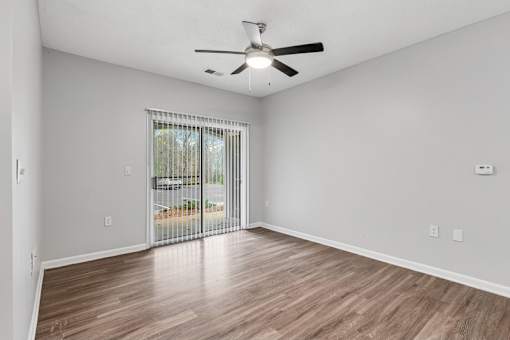 A room with a ceiling fan and sliding glass doors leading to a patio.
