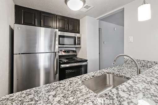 A kitchen with a stainless steel refrigerator and microwave.