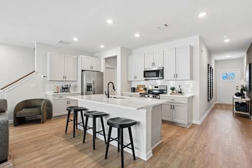 A modern kitchen with white cabinets and black stools.