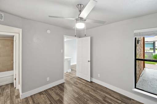 A room with a ceiling fan and a window showing an outdoor view.