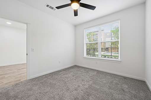 A room with a ceiling fan and a window with blinds.