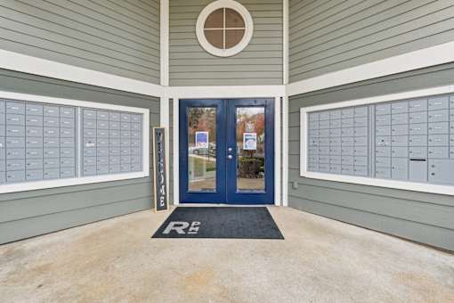 A blue door with a glass window is flanked by two mailboxes.