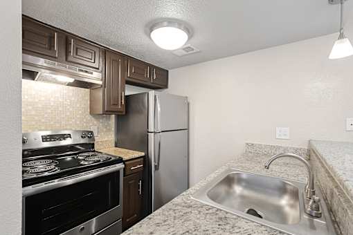A kitchen with a stove, sink, and refrigerator.
