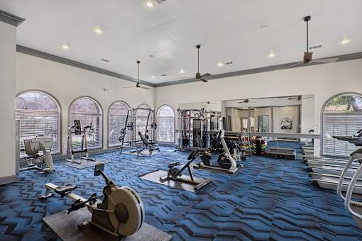 A spacious gym with a variety of equipment and a large mirror on the wall.