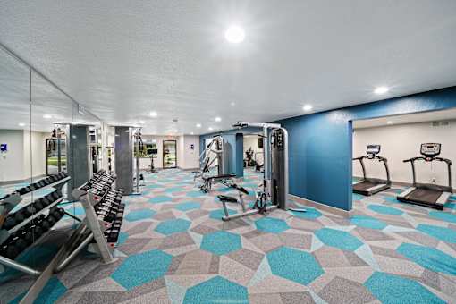 A gym with a variety of equipment including treadmills, weights, and exercise bikes.