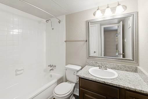 A white bathroom with a toilet, sink, and mirror.