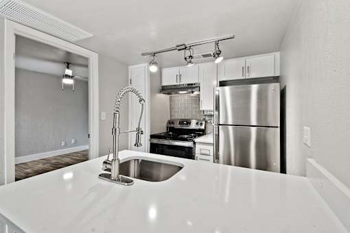A modern kitchen with a stainless steel refrigerator and a white countertop.