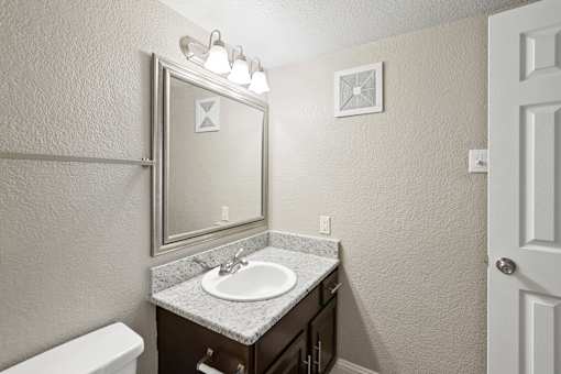 A bathroom with a sink, mirror, and toilet.