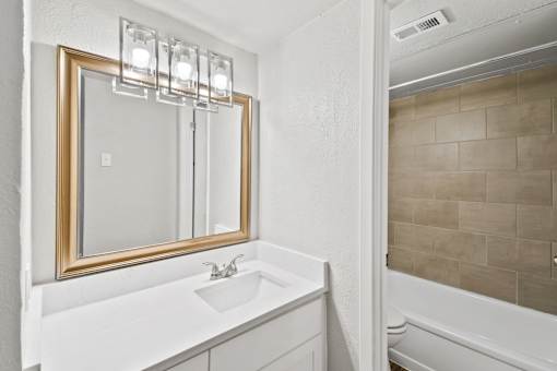 A bathroom with a white sink and a mirror with lights.