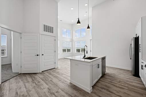 A modern kitchen with white cabinets and a wooden floor.
