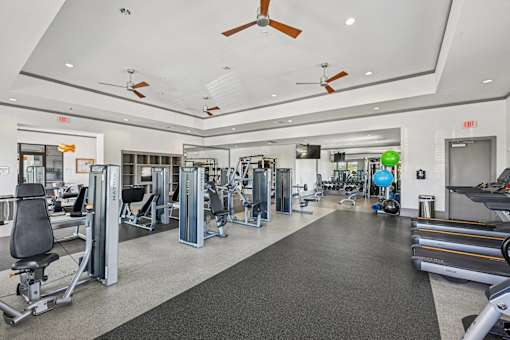 A spacious gym with a variety of equipment and a treadmill on the right side.
