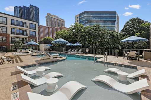 A pool with a modern design and white chairs around it.