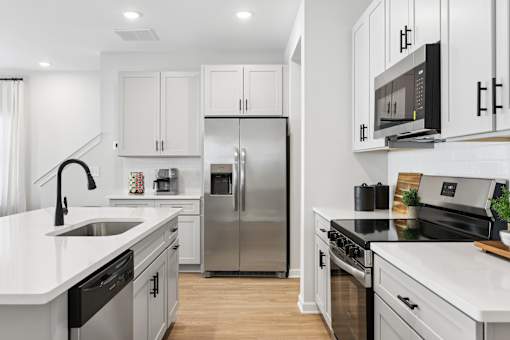 A modern kitchen with stainless steel appliances and white cabinetry.