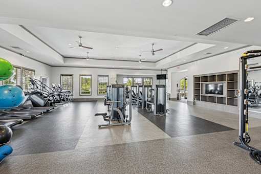 A spacious gym with a variety of equipment and a green exercise ball.