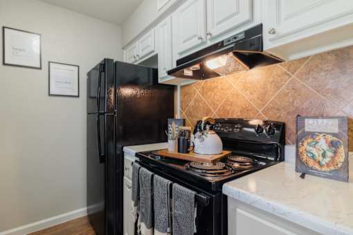 A kitchen with a black refrigerator and stove top oven.