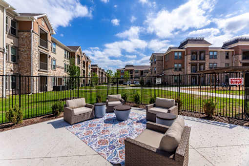 A patio with a rug and chairs in front of apartment buildings.