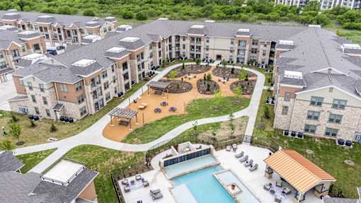 An aerial view of apartment buildings with a pool and a playground.