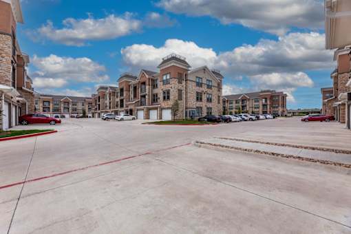 A parking lot in front of a large apartment complex.