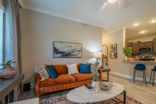 a living room with a couch coffee table and a kitchen in the background