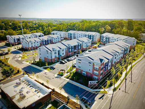A large apartment complex with a parking lot in front.
