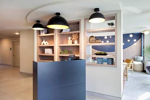 A modern interior with a black reception desk and a shelf with decorative items.