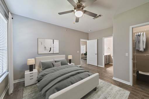 A bedroom with a bed, nightstands, and a ceiling fan.