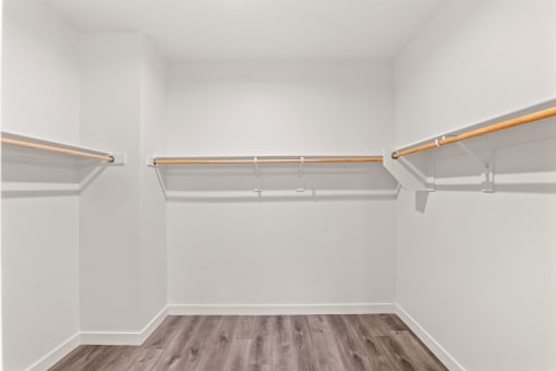 an empty room with white walls and wooden floors and a white closet with empty shelves